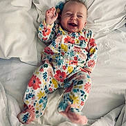 Lakota is registered to the contest to win money with this photo: baby, bed, bedding, blanket, cozy, cute, feet, floral_pajamas, hand, happy, infant, laughing, lying_down, newborn, nursery, onesie, pacifier, portrait, smiling, white_sheets