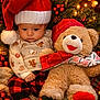 Joseph joined the competition — help win amazing prizes! baby, santa_hat, teddy_bear, plush_toy, christmas_decorations, holiday, festive_clothing, red_and_white, pine_branches, christmas_lights, cozy, cute, child, winter_clothing, patterned_pants, socks, soft_toy, holiday_season, warm_lighting, indoors