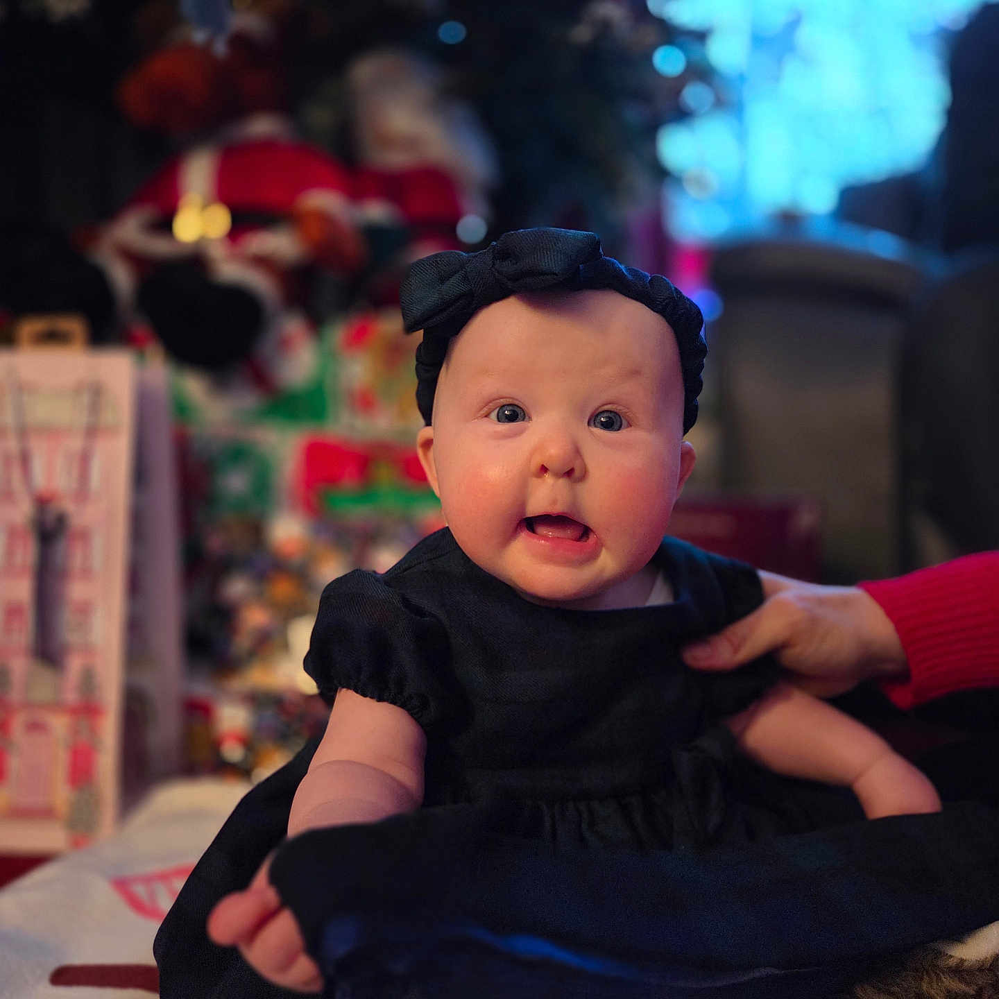 Marnie joined the competition — help win amazing prizes! baby, black_dress, blue_eyes, blurred_background, candid, child, cute, decorations, expression, face, festive, hand, headband, holiday, indoor, infant, person, sitting, soft_lighting, supporting_hand