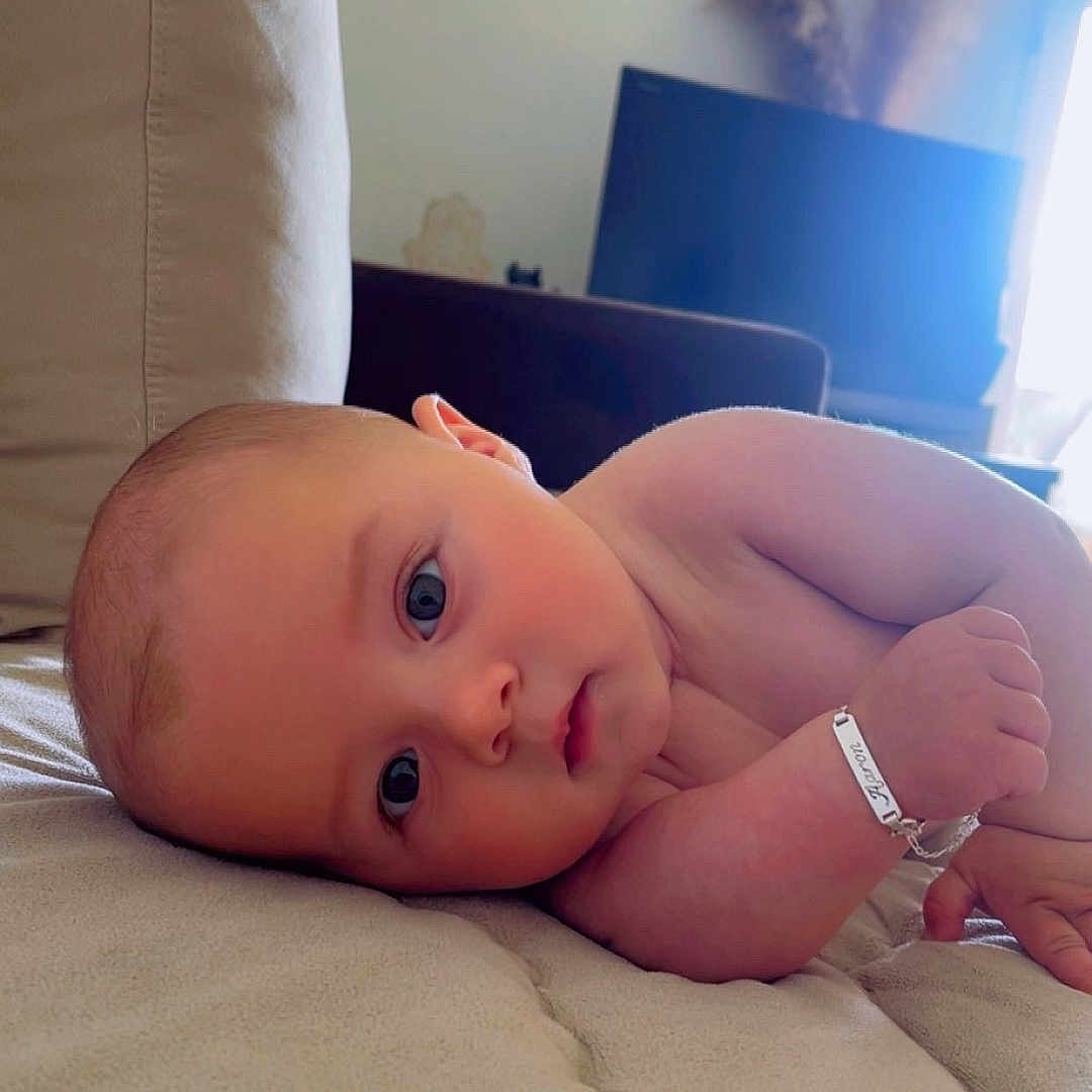 Aaron participe au concours pour gagner de l'argent avec cette photo : arm, baby, blue_eyes, bracelet, child, closeup, couch, cozy, curious, cute, face, furniture, home, indoor, infant, laying_down, person, portrait, skin, soft_lighting
