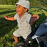 toddler, child, baby, grass, park, outdoor, sunlight, hat, striped_clothing, stroller, wheel, happy, laughing, cute, nature, greenery, trees, summer, playful, person