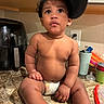 Karmelo joined the competition — help win amazing prizes! toddler, child, baby, diaper, hat, kitchen, countertop, appliance, cup, plastic, curious, sitting, indoors, person, face, skin, expression, looking_up, food_preparation, household