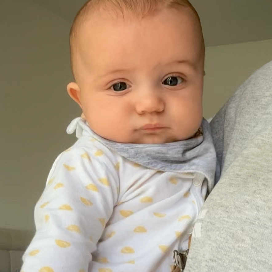 Gabriel participe au concours pour gagner de l'argent avec cette photo : baby, bib, child, clothing, cozy, cute, expression, eyes, face, fingernails, hand, head, holding, indoor, infant, pattern, person, skin, white, yellow