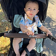 Kushim is registered to the contest to win money with this photo: baby, infant, child, stroller, cybex, canopy, seat, blanket, bib, pacifier_clip, short_sleeve, sunlight, shadow, sidewalk, grass, hands, feet, face, eyes, portrait
