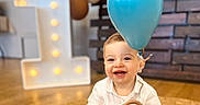 Elio participe au concours pour gagner de l'argent avec cette photo : baby, balloon, birthday, blue_balloon, blurred_background, celebration, child, cute, first_birthday, happy, indoor, marquee_light, number_one, portrait, smiling, teether, toy, wooden_beads, wooden_wall, woven_rug