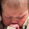 Griffin is registered to the contest to win money with this photo: baby, infant, face, hand, thumb, sleeping, skin, redness, hair, close_up, blanket, pattern, newborn, cute, peaceful, child, portrait, resting, soft, cozy