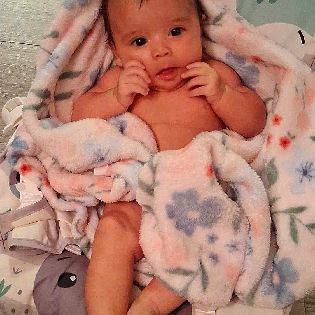 Mirna Guadalupe is registered to the contest to win money with this photo: animal_print, baby, baby_seat, barefoot, blanket, child, comfort, curious, cute, floral_pattern, indoors, infant, lying_down, pastel_colors, portrait, skin, small_hands, soft_texture, wooden_floor, young_child