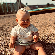 Jade participe au concours pour gagner de l'argent avec cette photo : baby, blond_hair, casual_clothing, child, chubby_arms, cute, daytime, hair_bow, happy, infant, natural_light, outdoor, pebbles, playground, playtime, short_sleeve_shirt, sitting, smiling, sunlight, toddler