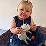 baby, child, pacifier, denim_dress, stuffed_animal, toy, bow, hair_accessory, barefoot, knitted_blanket, infant, cute, sitting, indoors, person, portrait, smiling, blue_eyes, skin, young