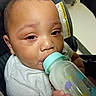 baby, bottle, car_seat, child, closeup, clothing, eyes, face, feeding, hair, hand, holding, indoor, infant, milk, milk_bottle, person, seat, warning_label, young_child