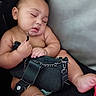 baby, sleeping, purse, black_purse, chubby, couch, furniture, hand, foot, skin, indoors, relaxing, peaceful, child, infant, face, closed_eyes, holding, seated, cute