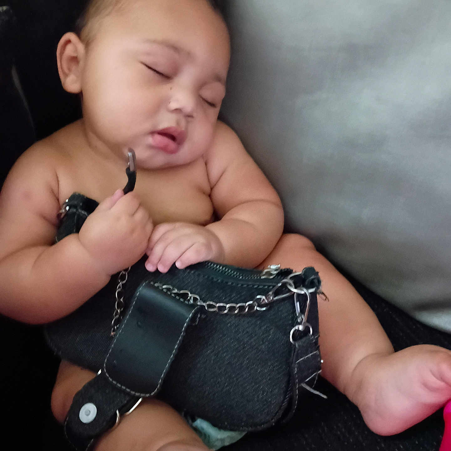 Cyairé is registered to the contest to win money with this photo: baby, sleeping, purse, black_purse, chubby, couch, furniture, hand, foot, skin, indoors, relaxing, peaceful, child, infant, face, closed_eyes, holding, seated, cute