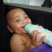 Cyairé is registered to the contest to win money with this photo: baby, blanket, bottle, child, closeup, couch, cozy, cute, expression, face, feeding, hand, happy, indoor, infant, milk, nurturing, purple, skin, smile