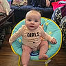 Paisley is registered to the contest to win money with this photo: baby, child, onesie, baby_chair, living_room, couch, pillow, bag, floor, wood_floor, person, sitting, face, blue, yellow, pink, clothing, furniture, indoor, cute
