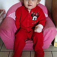 Lia participe au concours pour gagner de l'argent avec cette photo : casual, child, clothing, curly_hair, cute, expression, face, furniture, hand_wrapped, home, indoor, minnie_mouse, pink_chair, portrait, red_onesie, sitting, small_chair, tile_floor, toddler, young_child