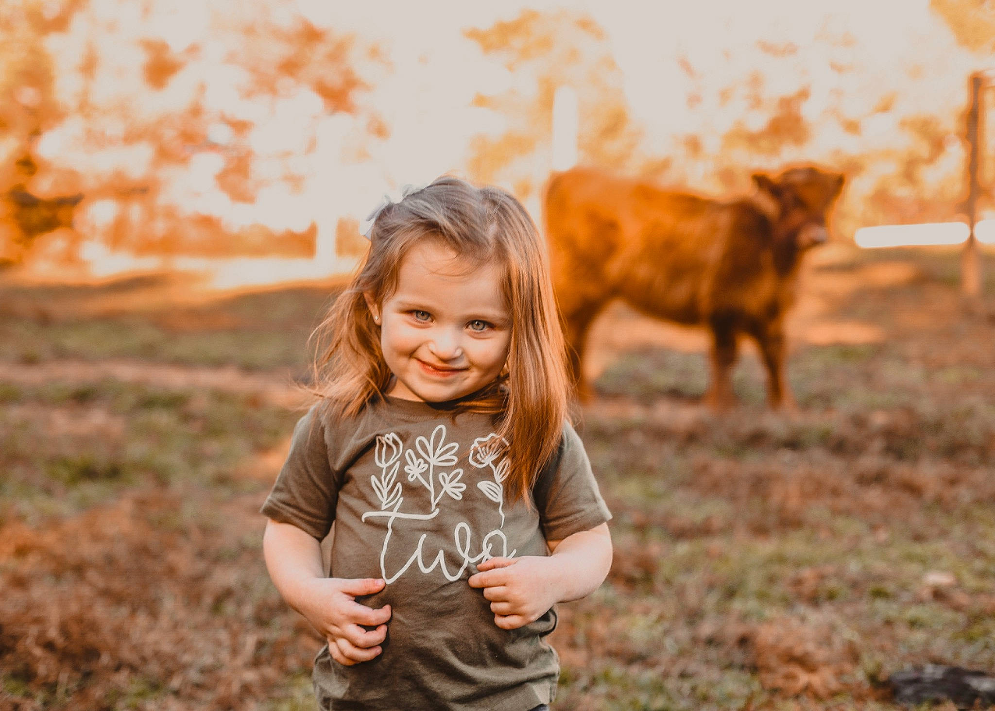 Charlee is registered to the contest to win money with this photo: blond, flash_photography, fun, grass, grassland, grazing, happy, joy, landscape, livestock, people_in_nature, person, plant, sky, smile, soil, sunlight, t_shirt, terrestrial_animal, toddler