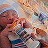 newborn, baby, infant, bottle, feeding, sleepy, hospital, hospital_bedding, striped_clothing, hat, adult_hand, portrait, closeup, indoors, cozy, blanket, bed, milk, formula, family