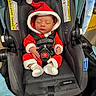 baby, newborn, sleeping, santa_suit, red_clothing, car_seat, infant, face, closed_eyes, fuzzy_trim, striped_socks, safety_harness, indoors, portrait, holiday, christmas, cozy, seated, blanket, photography