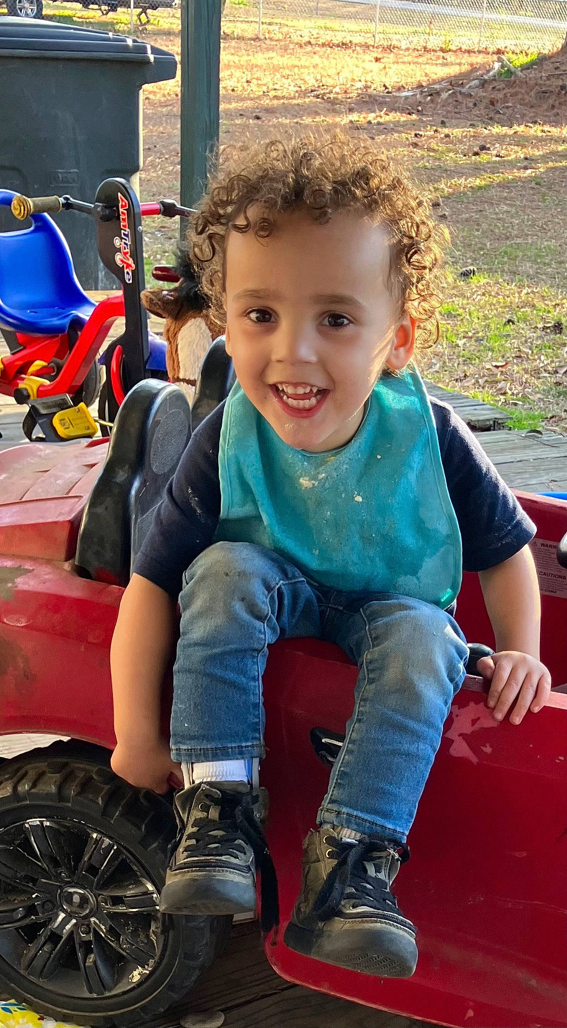 Jaxon is registered to the contest to win money with this photo: automotive_tire, blue, child, cool, electric_blue, facial_expression, fun, grass, happy, leg, leisure, motor_vehicle, person, play, recreation, smile, sneakers, summer, tire, toddler