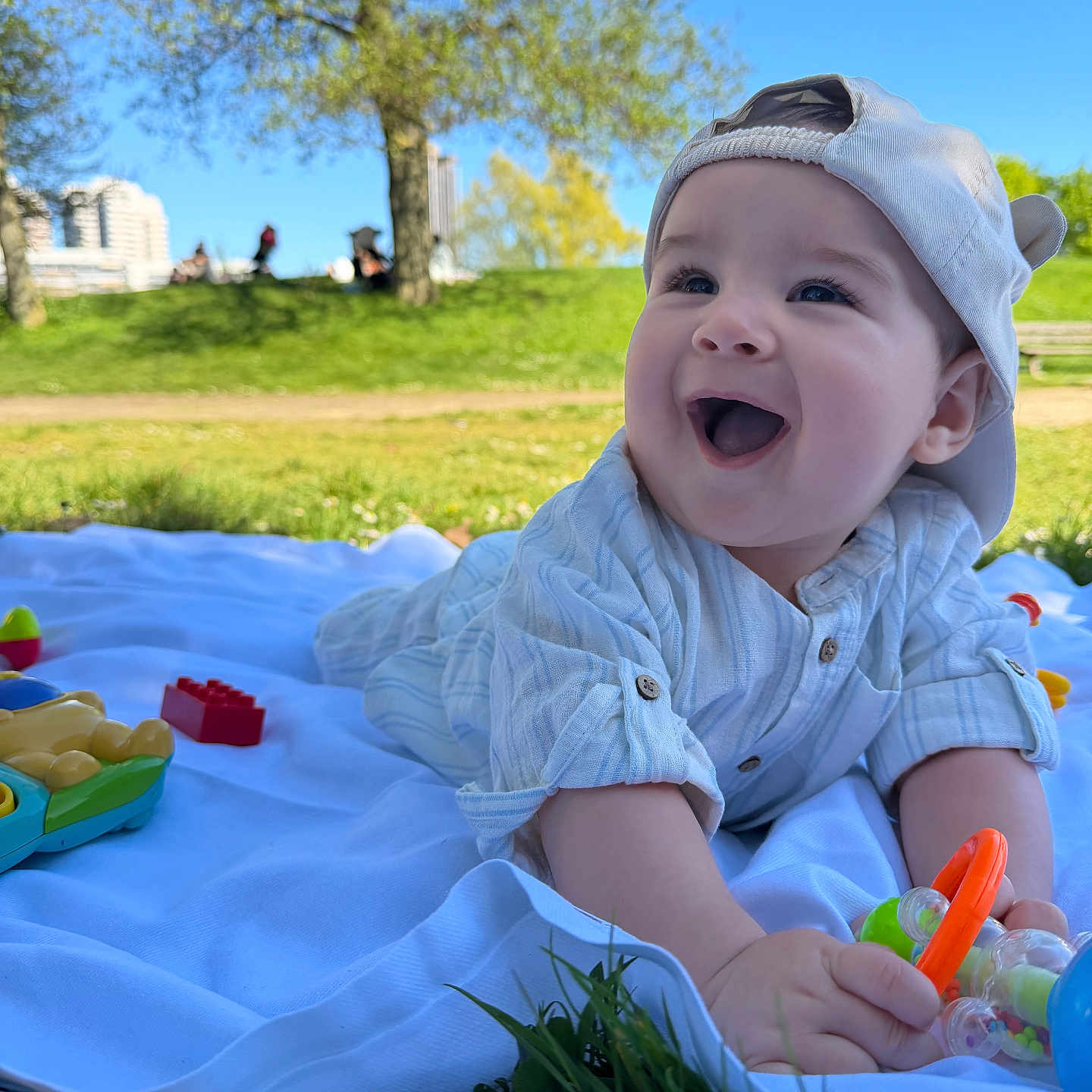 Selyan a rejoint le concours — aidez-le/la à gagner de superbes lots ! baby, child, outdoor, smiling, happy, grass, tree, blue_sky, hat, toy, blanket, shirt, playing, daylight, nature, park, infant, cute, person, face