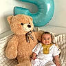 Selyan a rejoint le concours — aidez-le/la à gagner de superbes lots ! baby, teddy_bear, balloon, number_5, plush_toy, blanket, white_clothing, smiling, indoor, celebration, child, cute, soft_texture, portrait, sitting, decor, festive, toy, home, infant