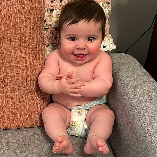 Elizabeth Or Ellie is registered to the contest to win money with this photo: baby, child, comfort, couch, cozy, cute, diaper, expression, face, hair, happy, indoor, infant, person, pillows, plush, sitting, skin, smiling, young
