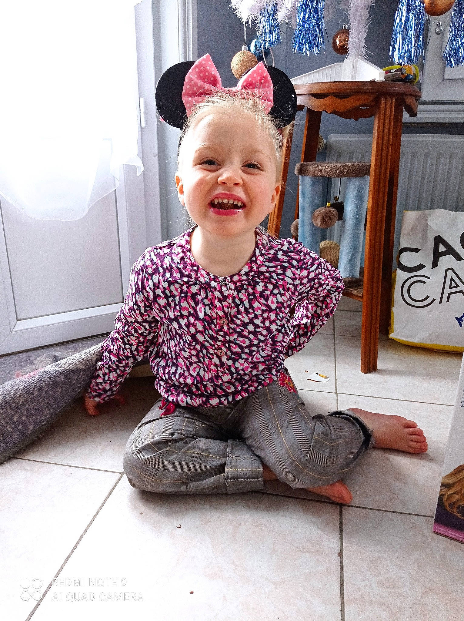 Thea participe au concours pour gagner de l'argent avec cette photo : baby, baby_toddler_clothing, blue, child, dress, event, floor, flooring, happy, magenta, pattern, person, purple, sitting, sleeve, smile, standing, textile, toddler, white