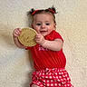 baby, infant, child, girl, pigtails, red_bows, red_shirt, checkered_shorts, carpet, floor, wooden_sign, five_months, smiling, cute, lying_down, indoor, portrait, happy, hands, face