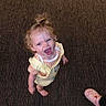 Pynelopi joined the competition — help win amazing prizes! child, toddler, smiling, curly_hair, barefoot, yellow_overall, orange_checkered_shirt, carpet, indoor, footwear, pink_croc, person, happy, looking_up, standing, cute, playful, bright_eyes, hair_tied_up, small_person