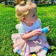 Pynelopi joined the competition — help win amazing prizes! toddler, child, grass, park, toy, plastic_eggs, tutu, rainbow_leggings, pony_tail, outdoor, sunny, people, trees, playing, cute, sitting, colorful, daytime, young_child, nature