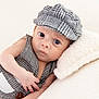 baby, infant, hat, vest, clothing, pillow, bed, face, eyes, expression, hand, skin, cute, portrait, newborn, lying_down, fashion, texture, soft, indoor
