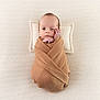 baby, swaddled, blanket, pillow, infant, newborn, wrapped, cozy, sleeping_area, bed, soft_texture, cute, small_hands, portrait, resting, peaceful, light_skin, indoors, lying_down, calm