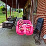 Rory is registered to the contest to win money with this photo: baby, swing, porch, pink, headband, child, outdoor, grass, brick_wall, chair, plant, hanging_plant, concrete, sunlight, toy, seat, foot, rope, window, bench