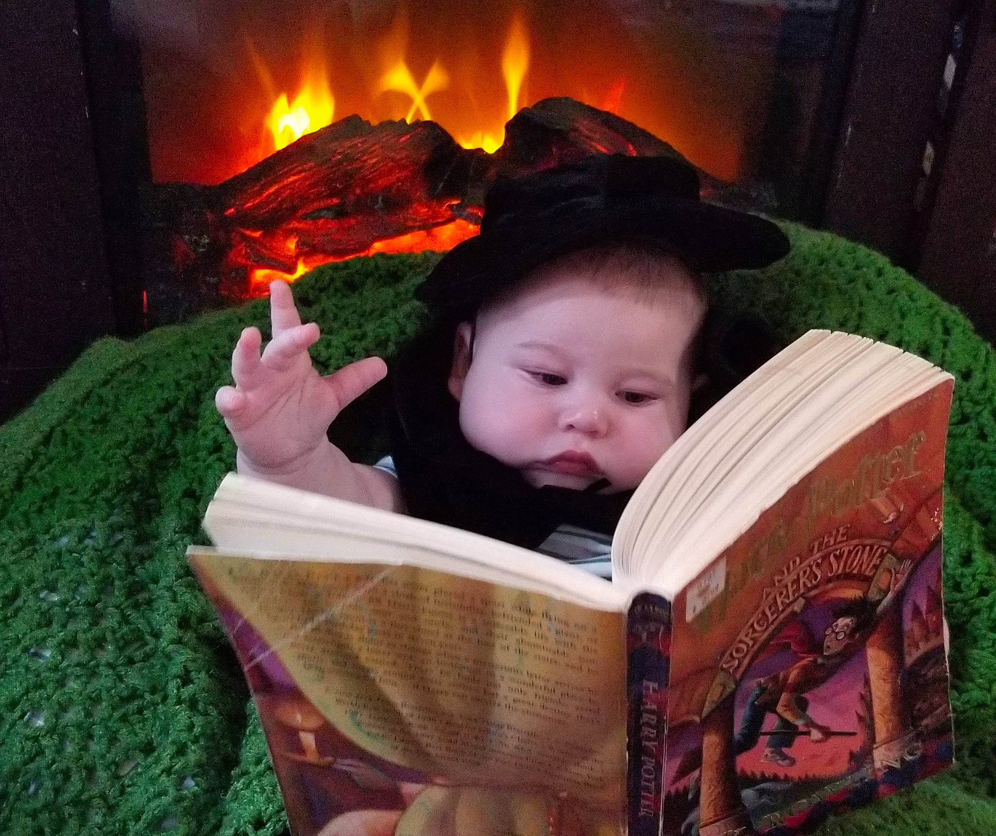 Sylas is registered to the contest to win money with this photo: baby, baby_toddler_clothing, book, child, comfort, eye, fire, fireplace, gas, grass, green, happy, hearth, heat, person, publication, reading, sitting, toddler, wood