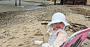 Isabella is registered to the contest to win money with this photo: baby, beach, chair, child, clothing, cloudy_sky, coast, footwear, hat, nature, outdoor, person, pier, pink, relaxation, rocks, sand, shore, summer, water