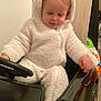 Leyten a rejoint le concours — aidez-le/la à gagner de superbes lots ! toddler, child, toy_car, onesie, white_clothing, indoor, cute, smiling, baby, plush, seat, steering_wheel, car_toy, floor, face, head, hand, furniture, wood_panel, play