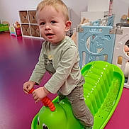 Leyten participe au concours pour gagner de l'argent avec cette photo : toddler, child, indoor, toy, rocker, green, caterpillar, playroom, purple_floor, storage, basket, clothing, socks, smile, play, person, young_child, furniture, plastic_toy, happy