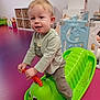 toddler, child, indoor, toy, rocker, green, caterpillar, playroom, purple_floor, storage, basket, clothing, socks, smile, play, person, young_child, furniture, plastic_toy, happy