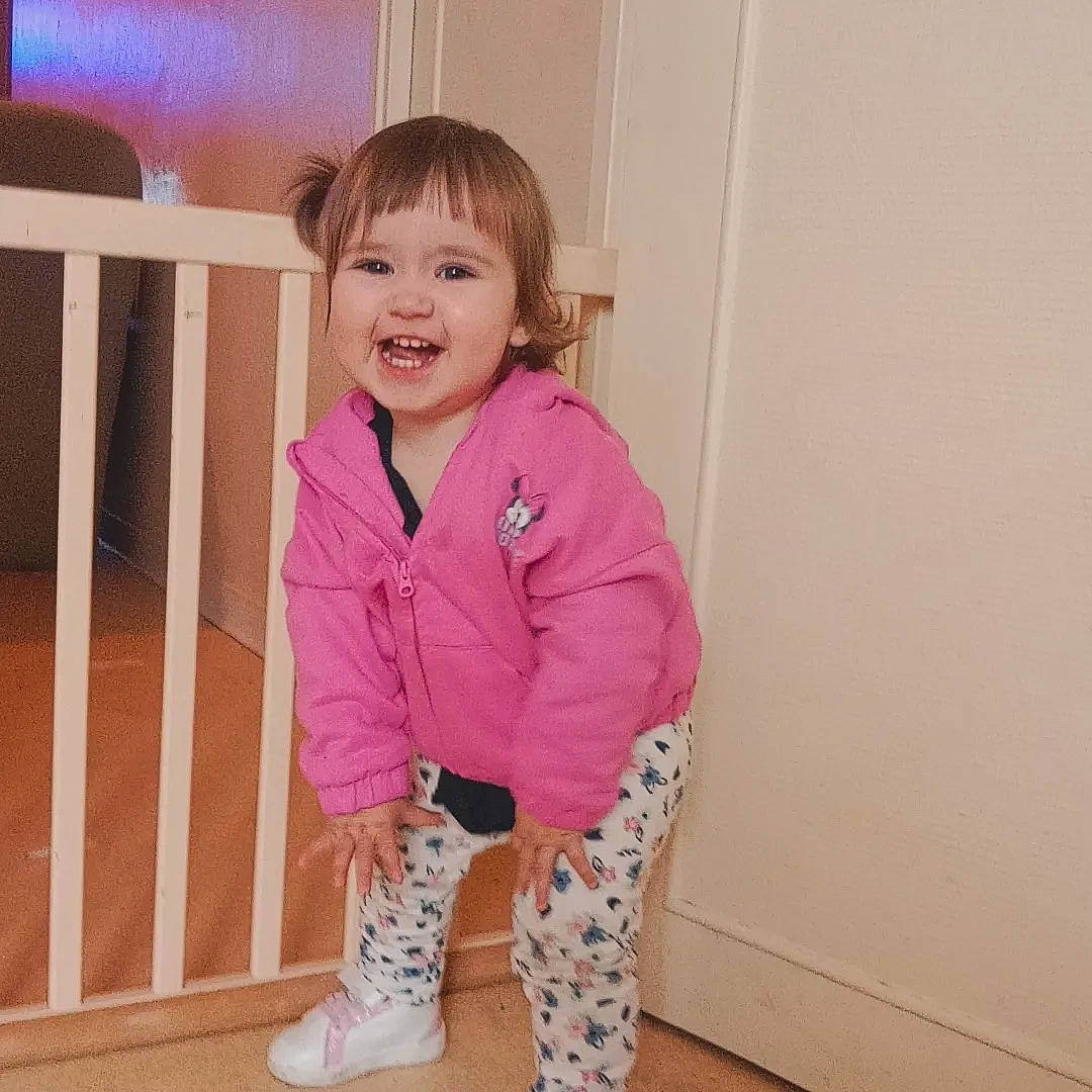 Lena a rejoint le concours — aidez-le/la à gagner de superbes lots ! baby_toddler_clothing, cheek, child, face, floor, flooring, happy, hardwood, human_leg, joy, knee, leg, magenta, outerwear, pattern, person, pink, sleeve, smile, thigh