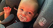 Draco is registered to the contest to win money with this photo: baby, infant, child, car_seat, pacifier, safety_harness, car, vehicle, sitting, waving, hand, blond_hair, blue_eyes, smiling, portrait, close_up, indoor, automotive,  안전, adorable