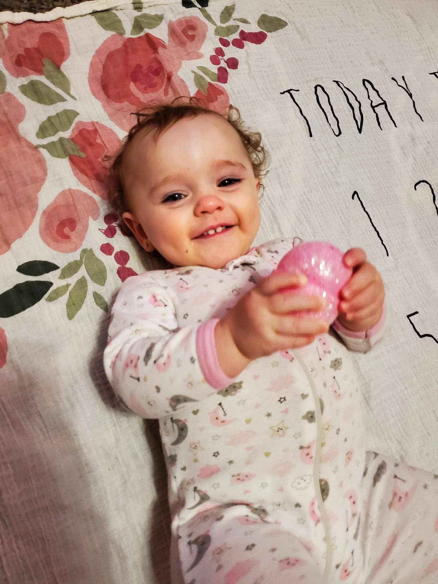 Emilee is registered to the contest to win money with this photo: arm, baby, baby_toddler_clothing, cheek, child, finger, flower, gesture, hand, happy, head, human, joy, lip, magenta, person, pink, skin, sleeve, smile