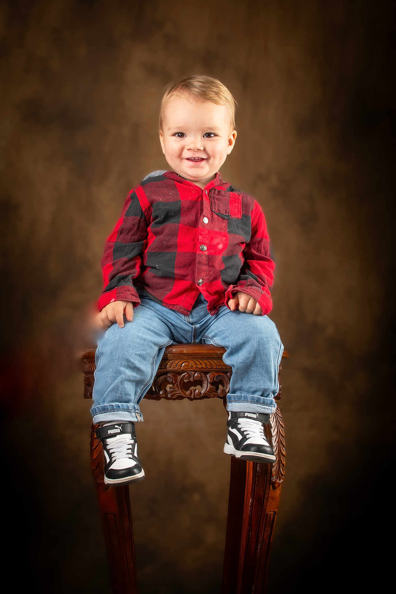Fabio participe au concours pour gagner de l'argent avec cette photo : brown_background, casual_clothing, checkered_shirt, child, cute, fashion, footwear, happy, indoor, jeans, portrait, puma, red_shirt, sitting, smile, sneakers, studio_portrait, toddler, wooden_stool, young_child