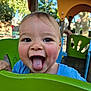 toddler, child, playground, green, tongue_out, happy, outdoor, smiling, blue_shirt, face, person, daylight, park, play_equipment, fun, cute, young, nature, trees, sunlight