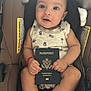 Liam joined the competition — help win amazing prizes! baby, infant, passport, car_seat, child, sitting, clothing, pineapple_print, red_bracelet, barefoot, face, eyes, hand, legs, travel, document, person, cute, indoor, comfort
