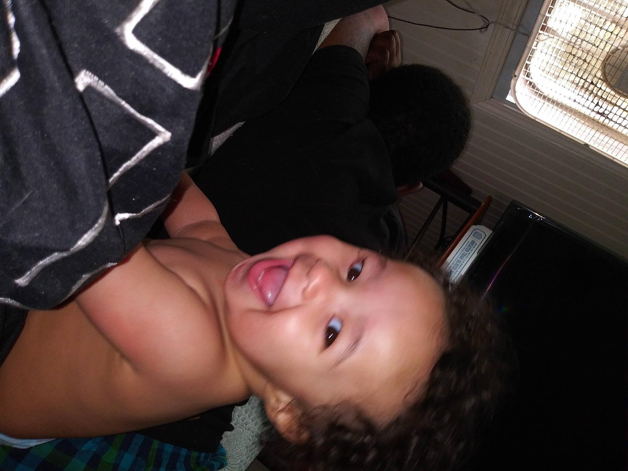 Tariq is registered to the contest to win money with this photo: abdomen, black, black_hair, chest, child, elbow, eyelash, flash_photography, fun, gesture, happy, human_leg, nose, person, room, sitting, smile, thigh, toddler, tree