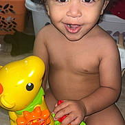 Zayden joined the competition — help win amazing prizes! toddler, child, toy, yellow_toy, giraffe_toy, smiling, curly_hair, indoor, play, happy, person, skin, face, hand, furniture, floor, colorful, baby, cute, expression