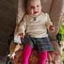 baby, baby_rocker, child, clothing, comfort, cute, floor, footwear, hair_bow, happy, indoor, infant, person, pink_tights, plaid_skirt, seat, sitting, smiling, toy, white_sweater
