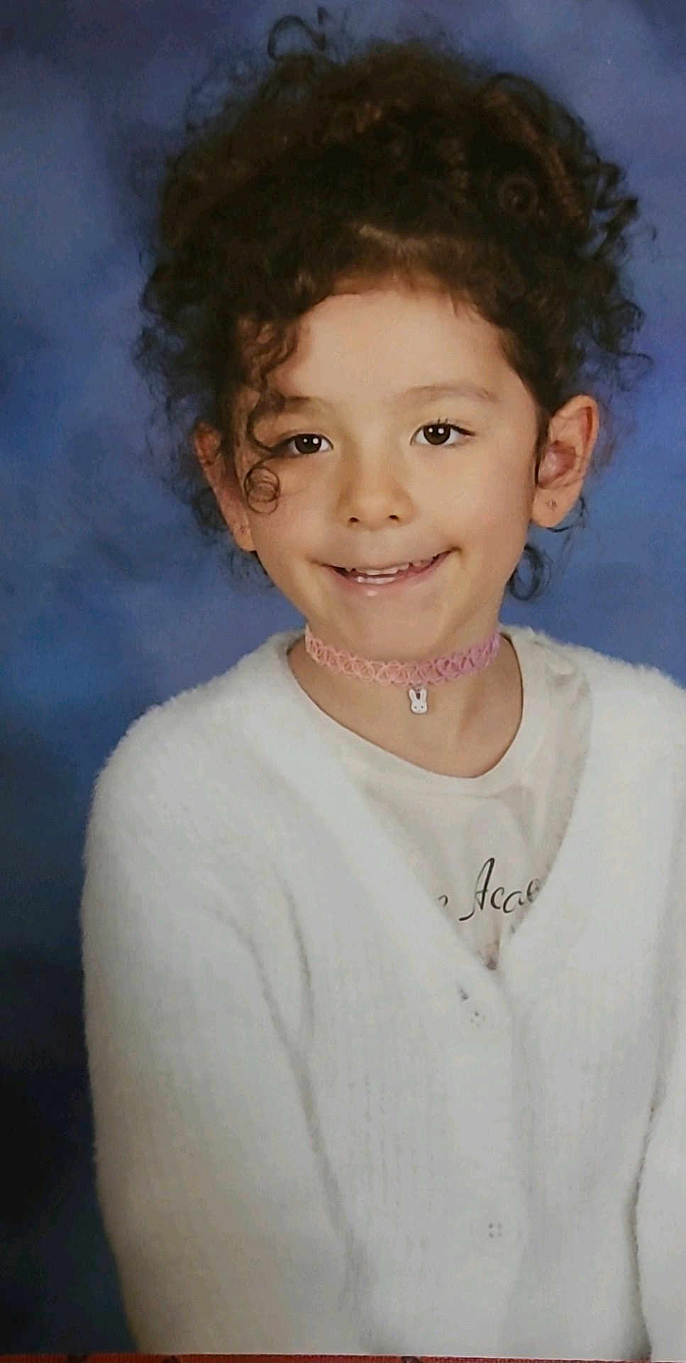 Eva Victoria joined the competition — help win amazing prizes! child, girl, curly_hair, smile, white_cardigan, pink_choker, bunny_pendant, portrait, studio_background, cute, young, fashion, accessory, happy, face, innocent, posing, casual_clothing, childhood, soft_lighting