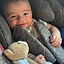 baby, child, car_seat, quilted, blanket, teddy_bear, soft_toy, smiling, happy, infant, face, hand, comfort, cozy, seat_belt, clothing, portrait, indoors, natural_light, cute