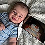James joined the competition — help win amazing prizes! baby, smiling, infant, blue_onesie, blanket, face, portrait, cute, lying_down, photo_print, bed, happy, child, indoors, toddler, patterned_blanket, closeup, person, newborn, cozy